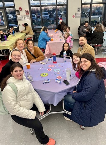 A group of people sit at a table and smile for a photo
