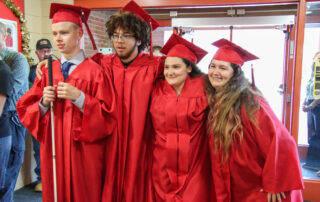 Four kids in red graduation attire pose for a photo