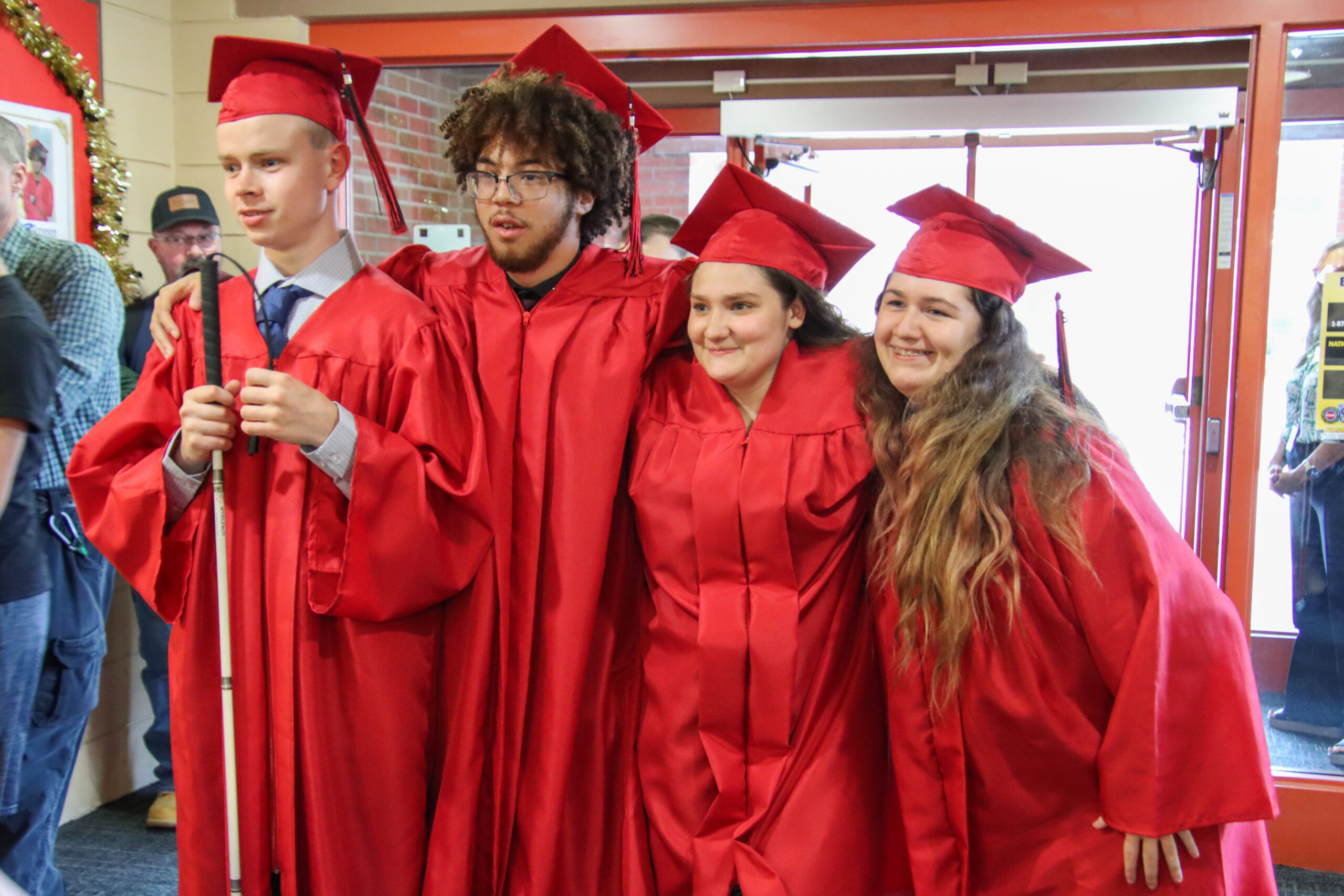 Four kids in red graduation attire pose for a photo