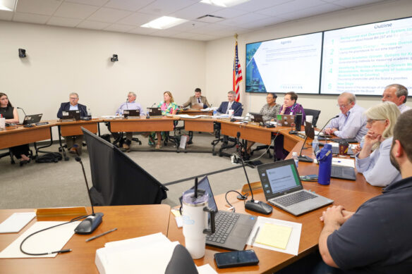 Members of the Kentucky Board of Education sit at tables setup in a semi-circle