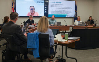 Robbie Fletcher sits in a boardroom, surrounded by a few members of the Teachers Advisory Council, speaking to them