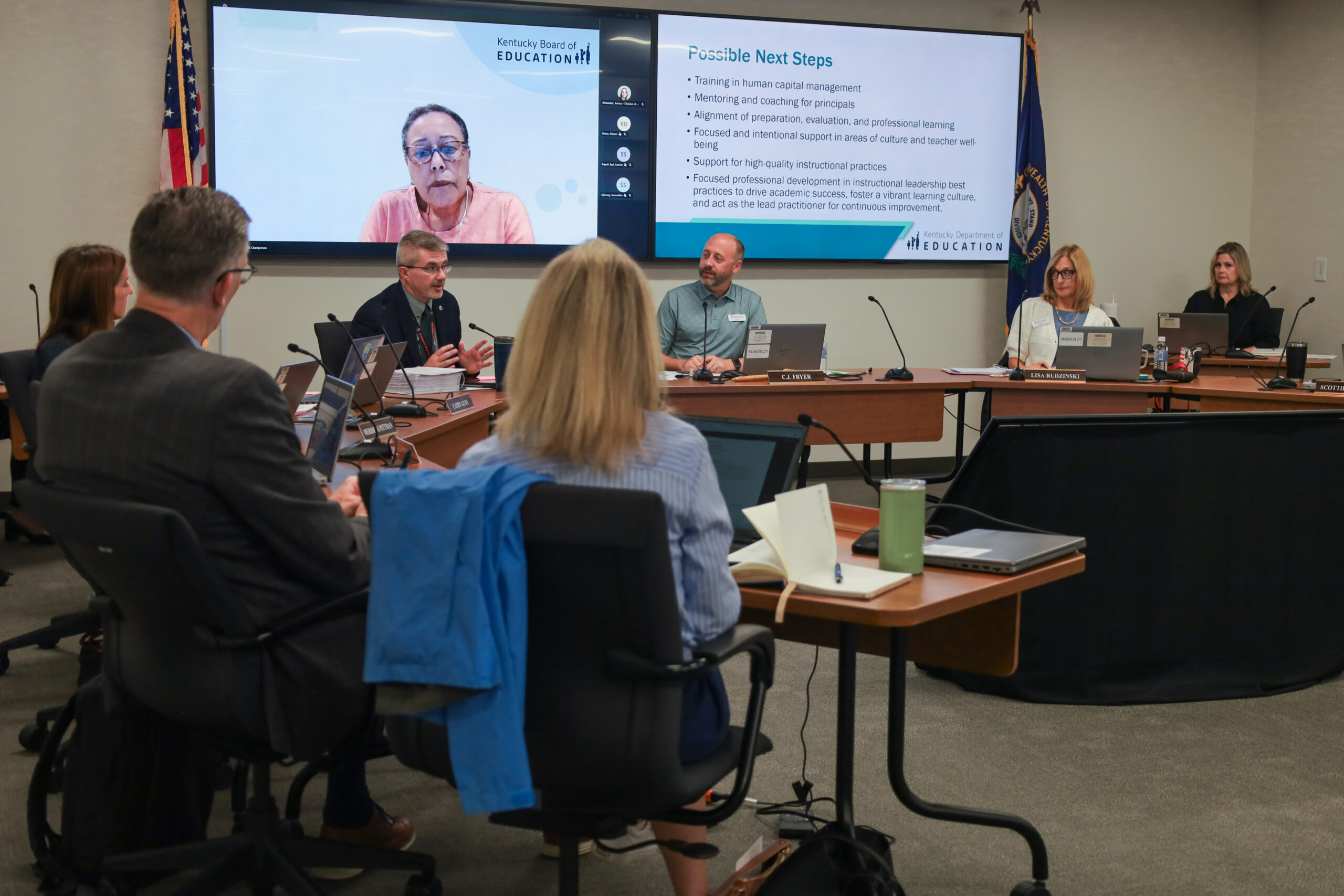 Robbie Fletcher sits in a boardroom, surrounded by a few members of the Teachers Advisory Council, speaking to them