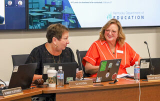 Two members of Kentucky Board of Education sit at a table.
