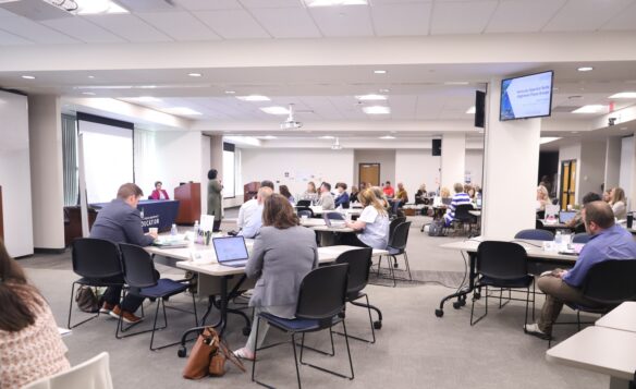 Group of people sitting at tables listening to a speaker