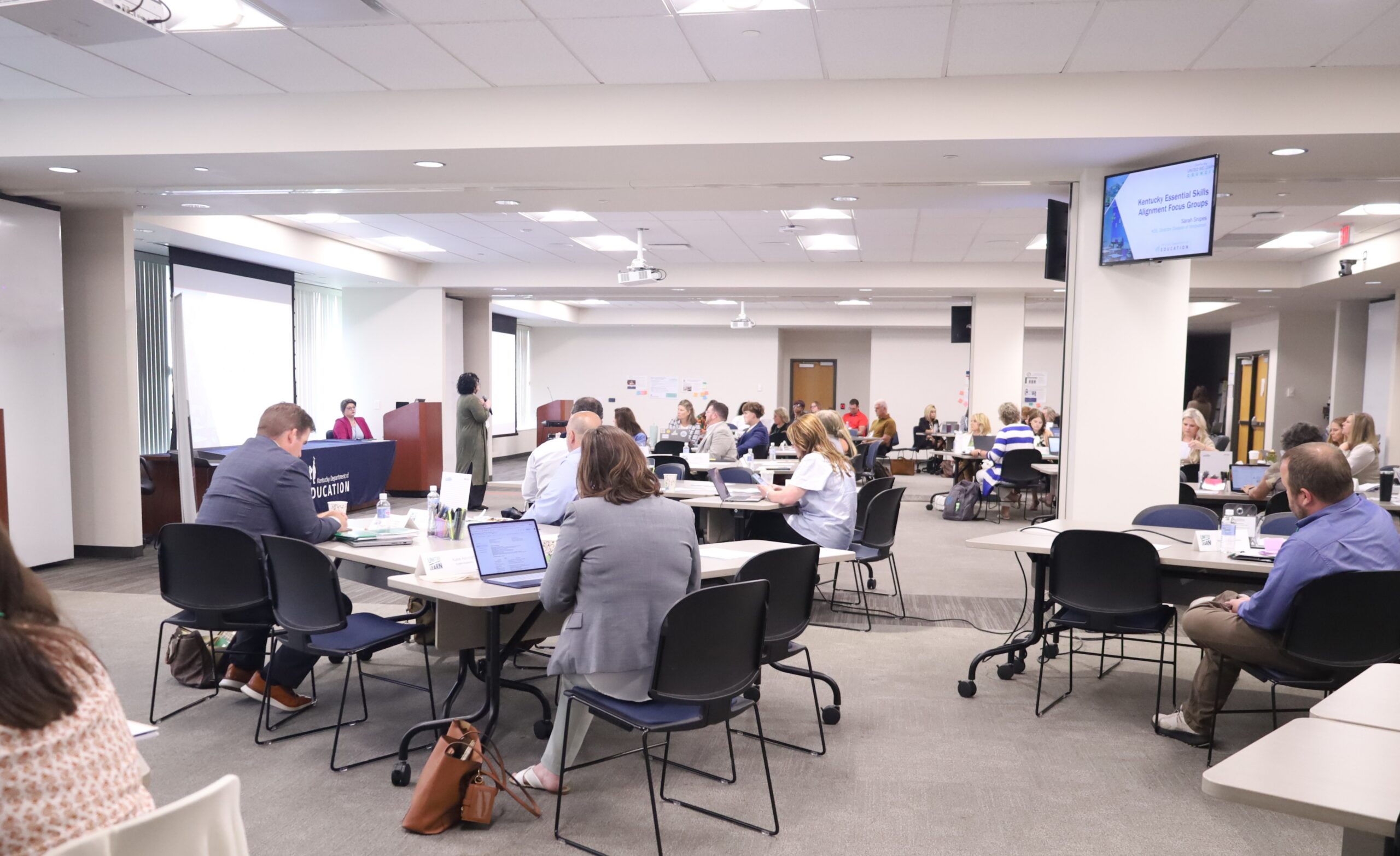 Group of people sitting at tables listening to a speaker
