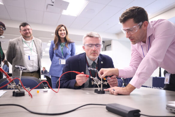 Two individuals using a soldering iron to construct an LED light.