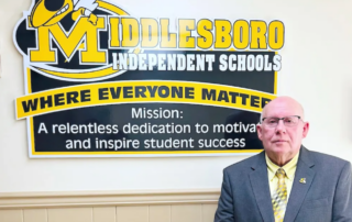 Bill Jones stands in front of a sign showing the name of the district, Middlesboro Independent Schools