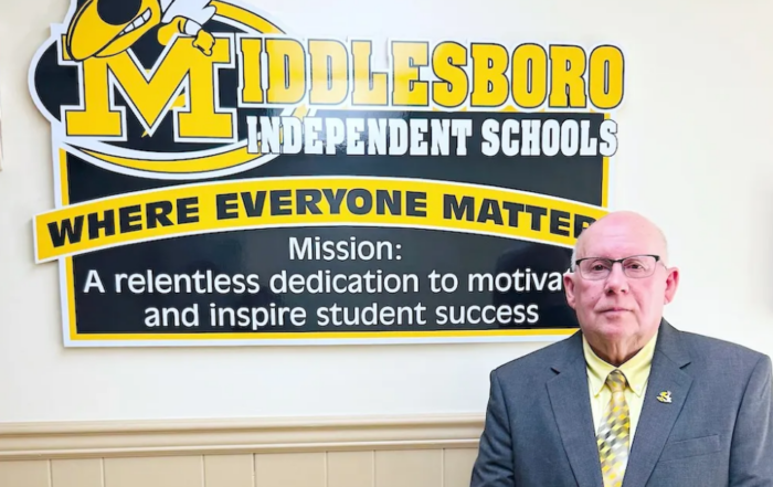 Bill Jones stands in front of a sign showing the name of the district, Middlesboro Independent Schools