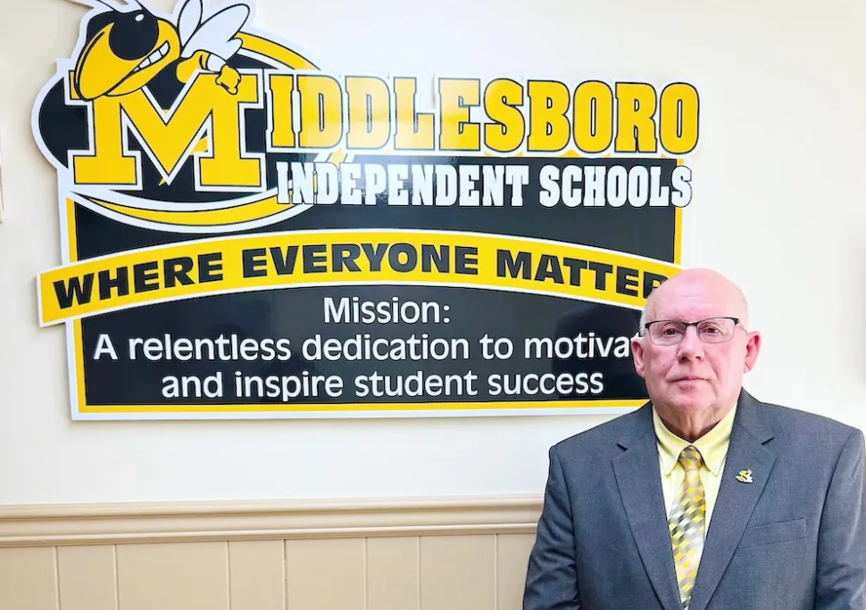 Bill Jones stands in front of a sign showing the name of the district, Middlesboro Independent Schools