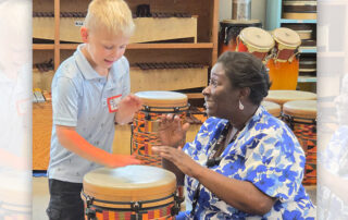 A teacher playing a drum with a student.