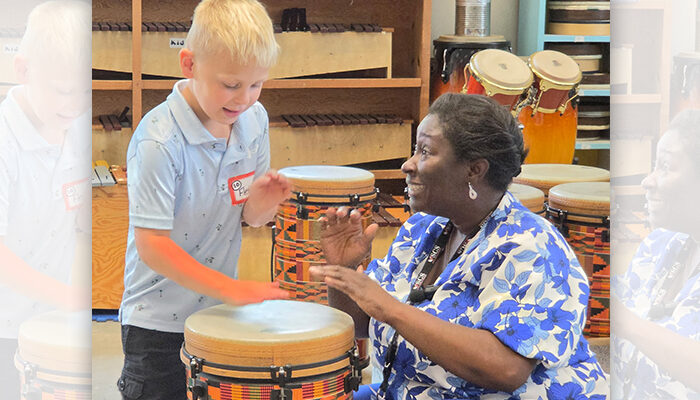 A teacher playing a drum with a student.