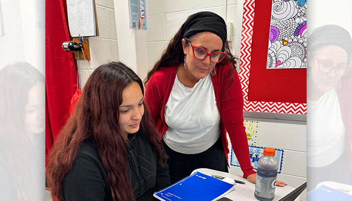 A teacher working with a student on a laptop.