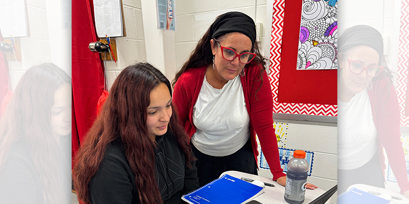 A teacher working with a student on a laptop.