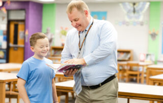 Kalem Grasham reads a book to a student in a library