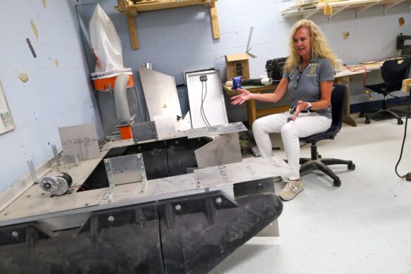 Elizabethtown High School (Elizabethtown Independent) Engineering Teacher Missy Mills sits in a chair by her student’s award-winning project, a robot designed by her students to automatically clean the local Freeman Lake. The robot has barrels on the bottom with flat metal plates on top