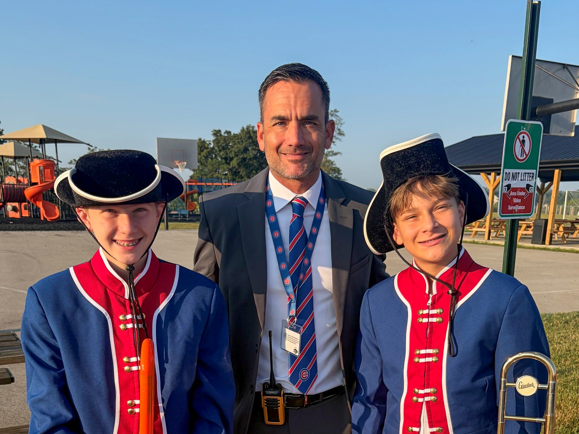 A man in a suit stands with two students in costumes