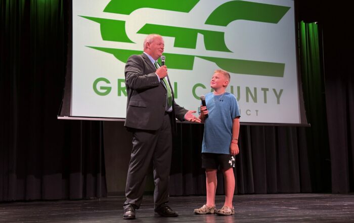 A man holds a microphone and stands on stage with a kid