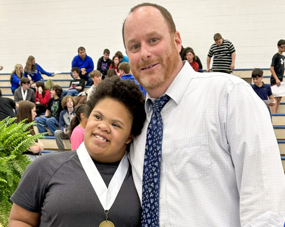 A man stands and poses for a photo with a student