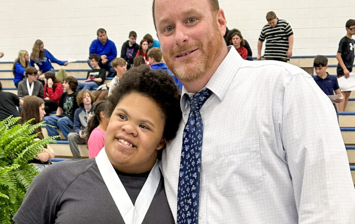 A man stands and poses for a photo with a student